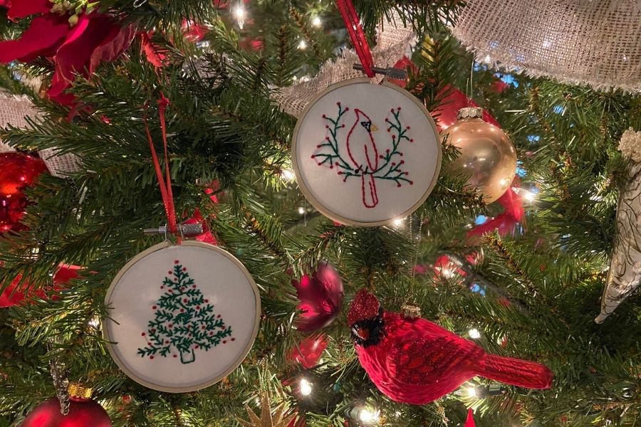 Two embroidery hoop ornaments featuring a Christmas tree and cardinal hanging on a tree.